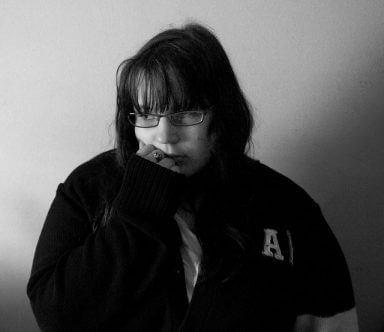 A girl in a large jacket looks sad as she wonders how to ease guilt in recovery