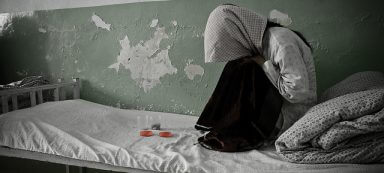 A girl hunches over on her bed because the person she just spoke with never thought about what not to say to a drug addict