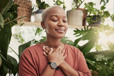 A young woman surrounded by plants practicing zen meditation.
