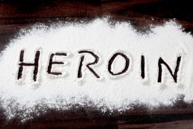 Heroin powder spelling the word heroin on a black surface
