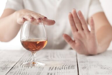 Person refusing a glass of wine on the table