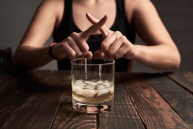 Woman making an X sign on a glass of whiskey