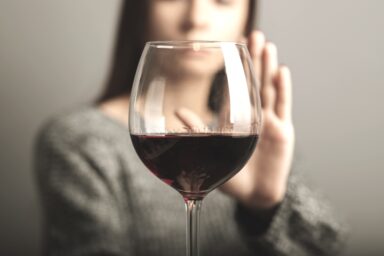 Woman rejecting a glass of wine with her hand