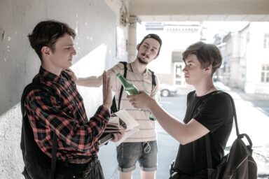 Two teenagers pressuring another teenager to drink alcohol