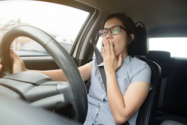 Woman yawning while driving a vehicle