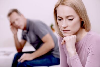 Woman looking pensive and depressed while her partner is on the background