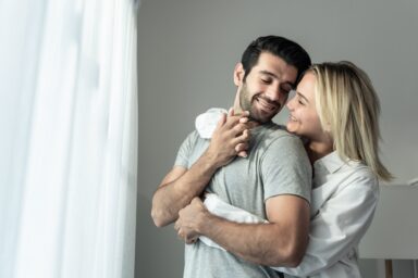 Man and woman hugging inside the bedroom, looking in love