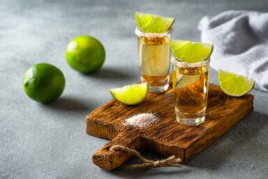 Tequila in two shot glasses with lime in the background