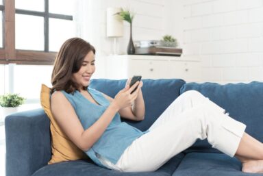 Woman lying on the couch reading her phone regarding quotes on sober living